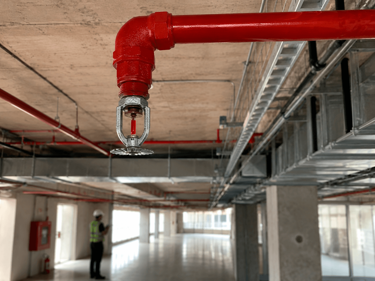 Sprinkler de sistema de incêndio instalado em edificação com tubulação vermelha e infraestrutura técnica aparente